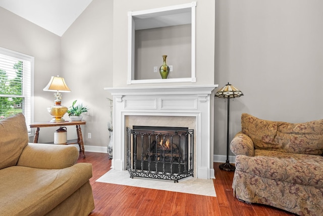 living room with a fireplace, wood finished floors, lofted ceiling, and baseboards