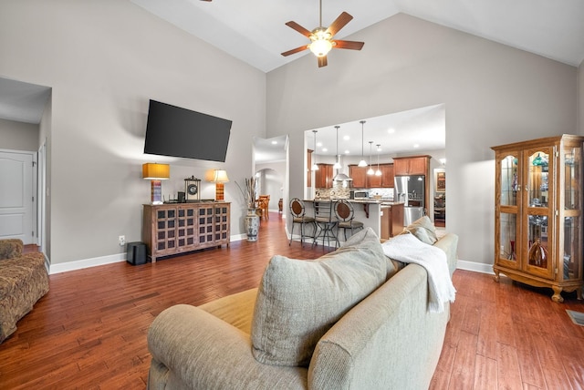 living room with ceiling fan, high vaulted ceiling, wood finished floors, baseboards, and recessed lighting