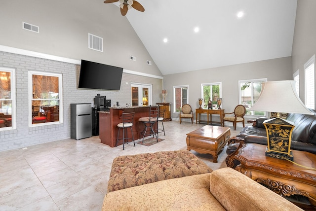 living room with high vaulted ceiling, a ceiling fan, brick wall, recessed lighting, and light tile patterned floors