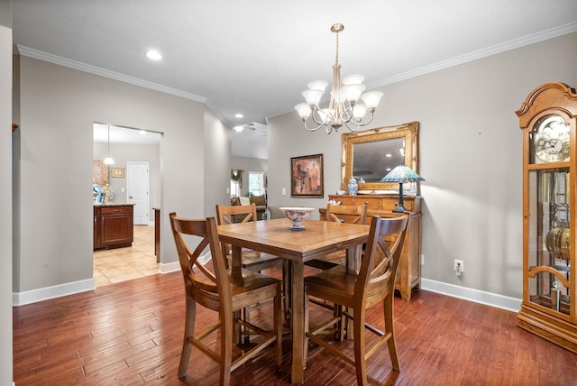 dining space with ornamental molding, light wood finished floors, a chandelier, baseboards, and recessed lighting