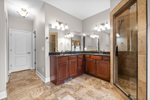 bathroom with a shower stall, double vanity, baseboards, and stone finish floors