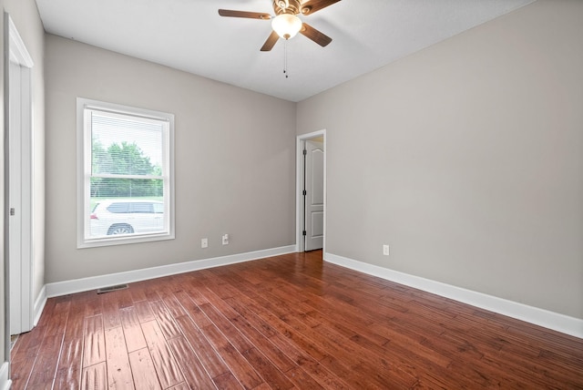 spare room featuring a ceiling fan, dark wood-style flooring, and baseboards