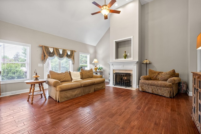 living room featuring a fireplace with flush hearth, ceiling fan, high vaulted ceiling, wood finished floors, and plenty of natural light