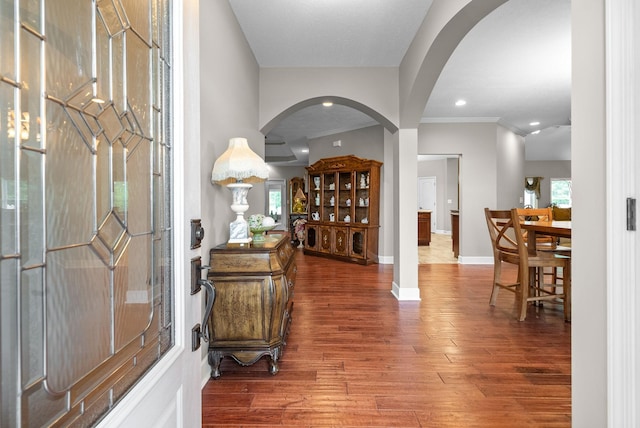 foyer entrance with arched walkways, wood finished floors, baseboards, crown molding, and recessed lighting