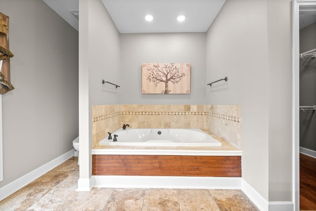 bathroom with a bath, baseboards, a walk in closet, toilet, and recessed lighting