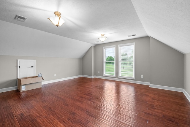 bonus room with vaulted ceiling, a textured ceiling, wood finished floors, and baseboards