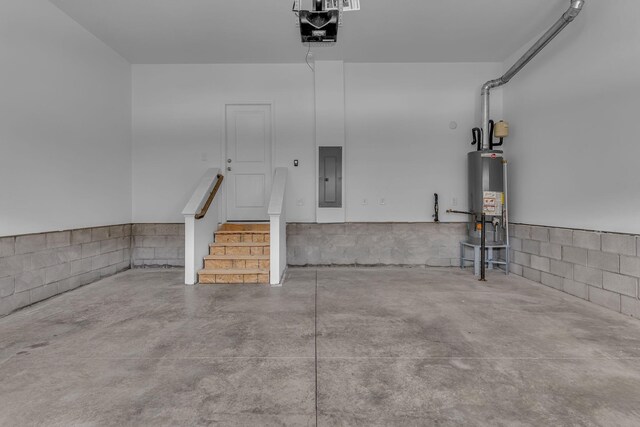 garage featuring gas water heater, electric panel, a garage door opener, and concrete block wall