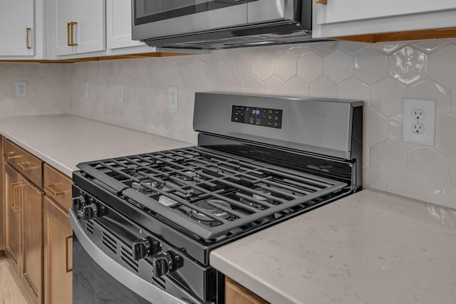 kitchen featuring appliances with stainless steel finishes, decorative backsplash, and light stone countertops