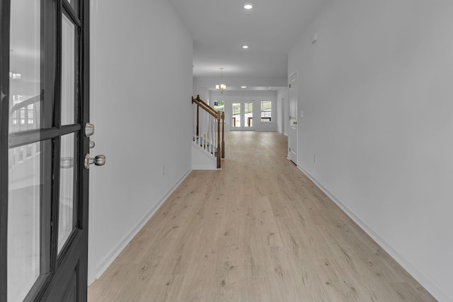 corridor with light wood finished floors, recessed lighting, stairs, baseboards, and a chandelier