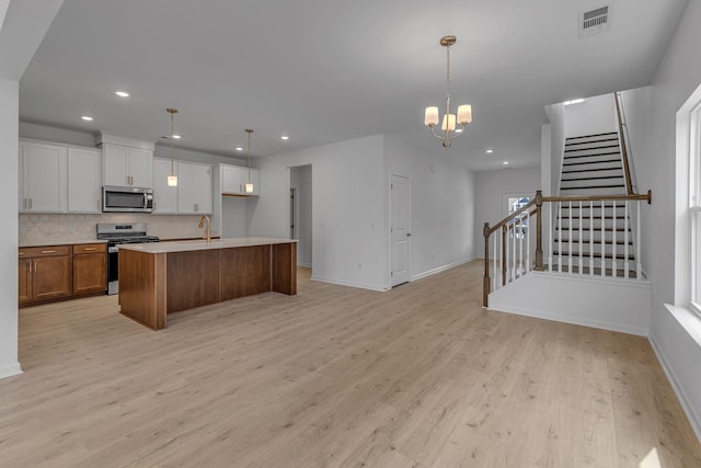 kitchen with appliances with stainless steel finishes, backsplash, light wood-style floors, pendant lighting, and recessed lighting