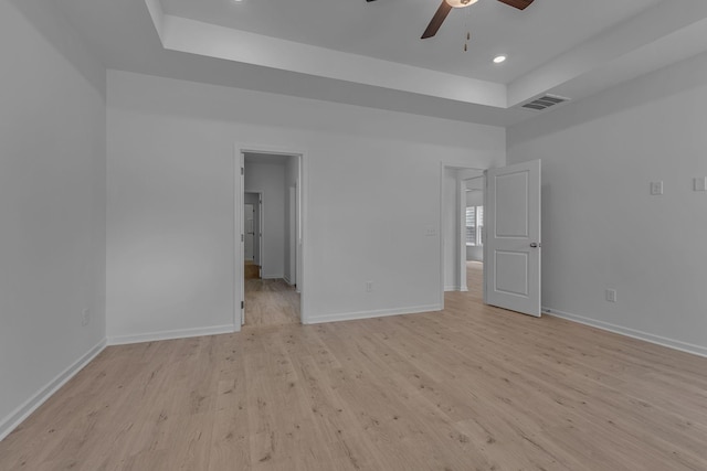 unfurnished bedroom with a tray ceiling, baseboards, light wood-style flooring, and recessed lighting