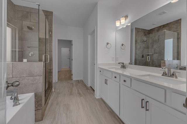 full bathroom with a shower stall, a bath, double vanity, and baseboards
