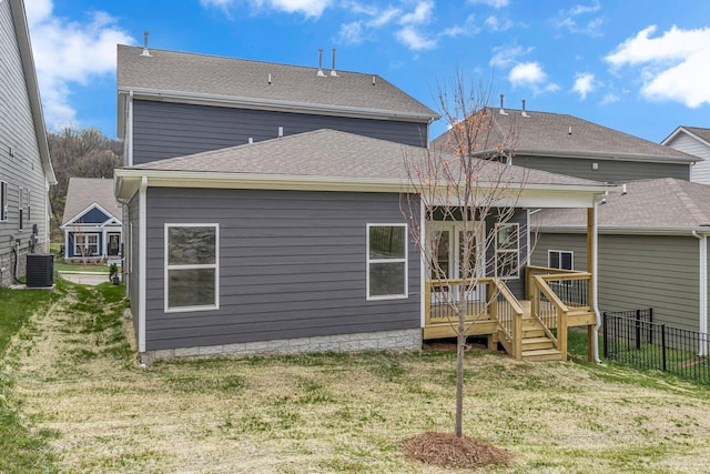 back of property with a wooden deck, central AC unit, and a shingled roof