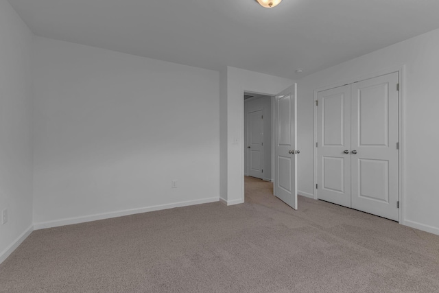 unfurnished bedroom featuring light colored carpet, baseboards, and a closet