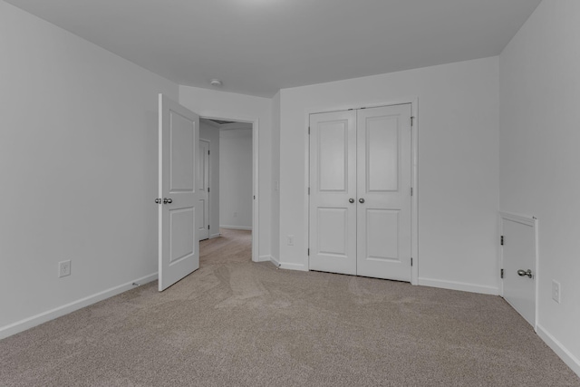 unfurnished bedroom with light carpet, baseboards, and a closet