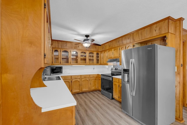 kitchen featuring stainless steel appliances, under cabinet range hood, a ceiling fan, light countertops, and light wood-style floors
