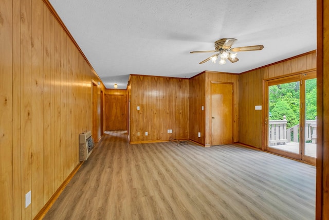 unfurnished living room featuring ceiling fan, light wood-style floors, wood walls, a textured ceiling, and baseboards