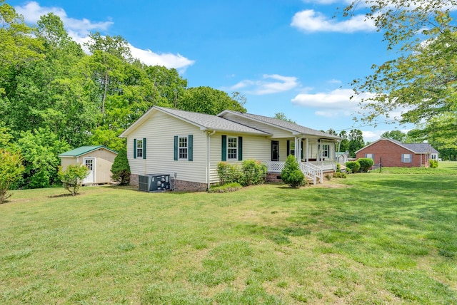 rear view of house featuring a porch, central AC, a yard, and an outbuilding
