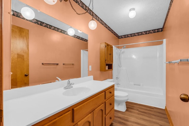full bathroom with wood finished floors, a textured ceiling, vanity, toilet, and shower / bath combination