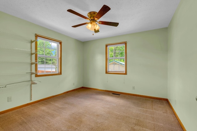 carpeted spare room with baseboards, ceiling fan, and a textured ceiling