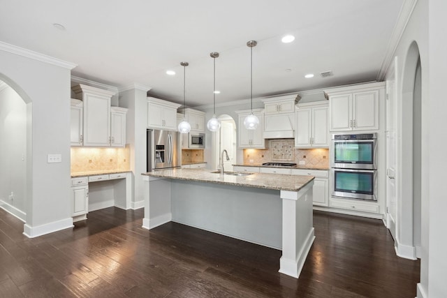 1000 Swanson Ln, Franklin, TN 37064 - kitchen featuring stainless steel appliances, a sink, arched walkways, decorative backsplash, and dark wood-style flooring
