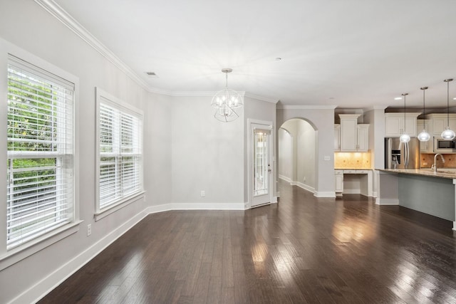 1000 Swanson Ln, Franklin, TN 37064 - unfurnished living room featuring a sink, arched walkways, a chandelier, dark wood-style flooring, and crown molding