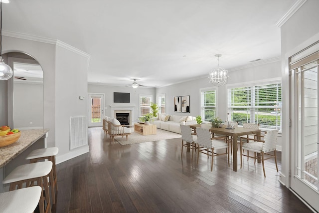 1000 Swanson Ln, Franklin, TN 37064 - dining space featuring a ceiling fan, a fireplace, dark wood-type flooring, arched walkways, and crown molding