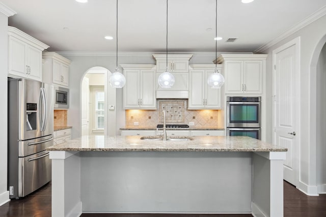 1000 Swanson Ln, Franklin, TN 37064 - kitchen featuring stainless steel appliances, arched walkways, dark wood-style flooring, a center island with sink, and crown molding