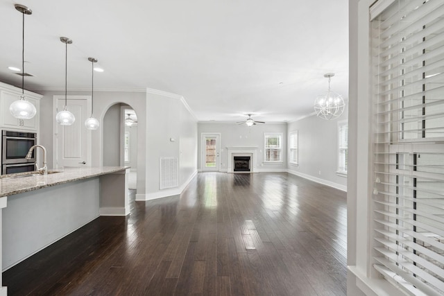 1000 Swanson Ln, Franklin, TN 37064 - unfurnished living room with a fireplace, a ceiling fan, arched walkways, a sink, and dark wood-style floors