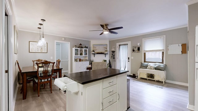 kitchen with dark countertops, light wood-style floors, open floor plan, a ceiling fan, and crown molding