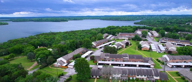aerial perspective of suburban area with a nearby body of water and a heavily wooded area