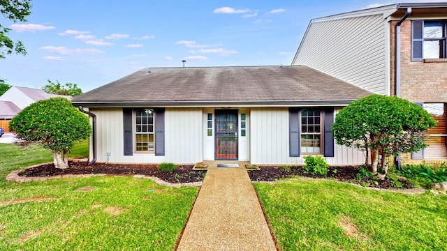 view of front of home with a front yard, board and batten siding, and a shingled roof