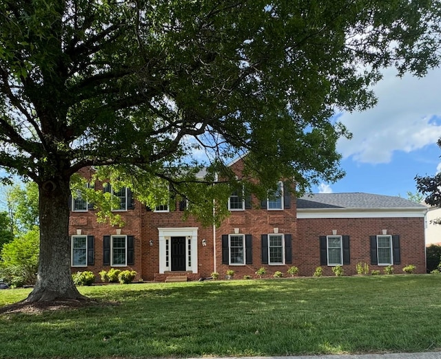 colonial home featuring a front yard and brick siding