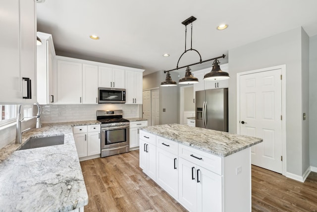 410 Springhouse Ct, Franklin, TN 37067 - kitchen featuring stainless steel appliances, a sink, a kitchen island, decorative backsplash, and light wood-style flooring