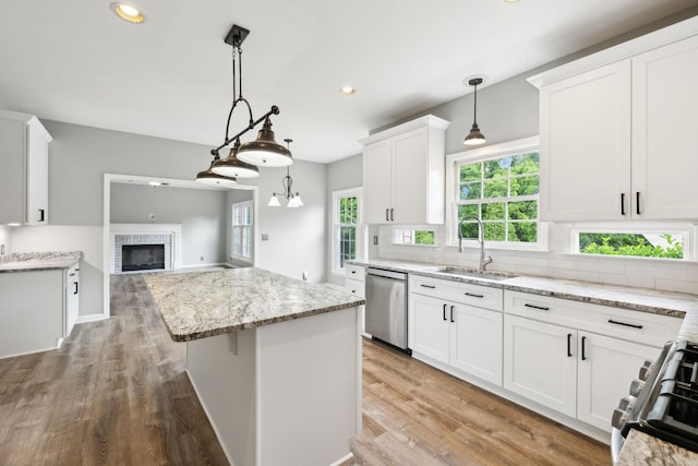 410 Springhouse Ct, Franklin, TN 37067 - kitchen with stainless steel appliances, a sink, white cabinets, a center island, and a brick fireplace