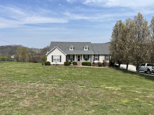 new england style home with a front yard, covered porch, and a shingled roof