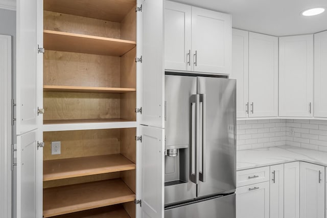 kitchen featuring high quality fridge, open shelves, white cabinetry, and light stone countertops