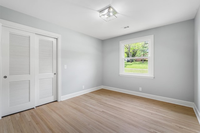 unfurnished bedroom featuring light wood-style floors, baseboards, and a closet