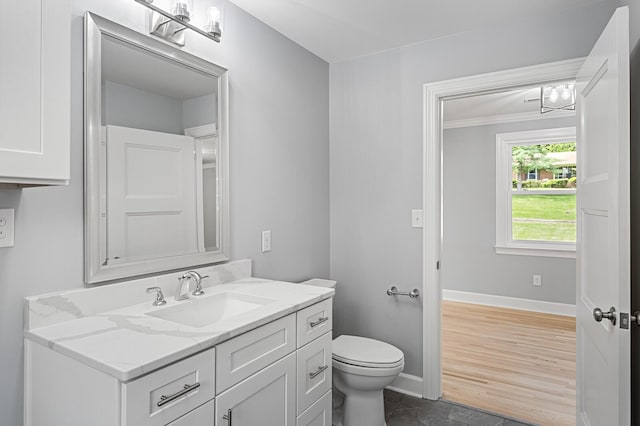 bathroom with toilet, vanity, baseboards, and ornamental molding