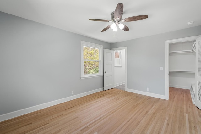 unfurnished bedroom featuring baseboards, light wood-style flooring, attic access, and a spacious closet