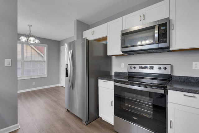 1493 Mcclardy Rd, Clarksville, TN 37042 - kitchen featuring appliances with stainless steel finishes, dark countertops, a chandelier, wood finished floors, and white cabinetry