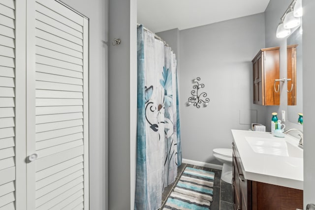 bathroom with vanity, toilet, baseboards, and curtained shower