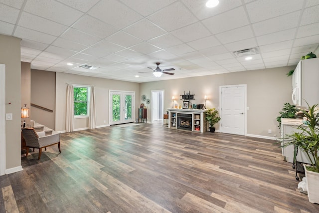 living room with wood finished floors, a ceiling fan, baseboards, a paneled ceiling, and stairway