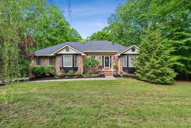 ranch-style house featuring brick siding, a front yard, and roof with shingles