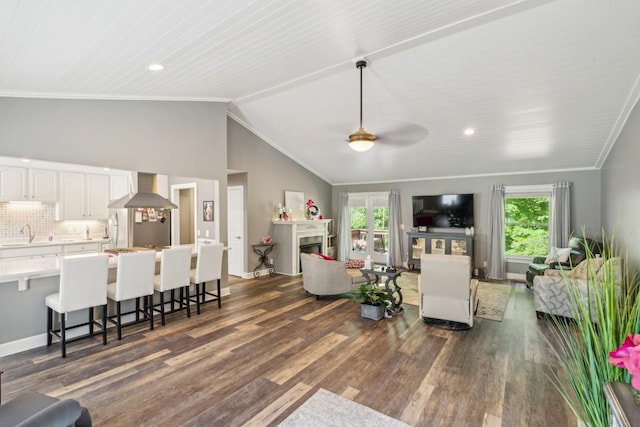 living area with plenty of natural light, dark wood-type flooring, a ceiling fan, crown molding, and lofted ceiling
