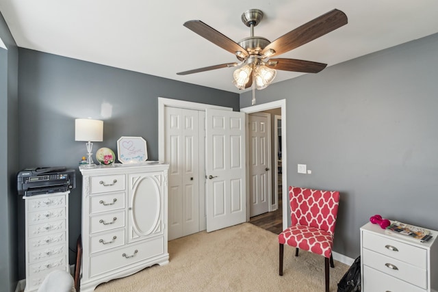 living area with a ceiling fan and light colored carpet