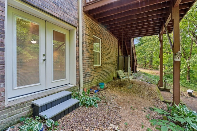 view of side of property featuring french doors, brick siding, entry steps, and an attached carport