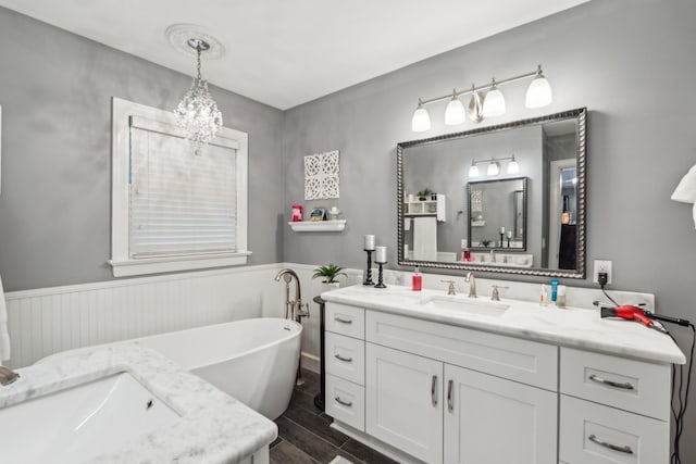 bathroom featuring vanity, a freestanding bath, a chandelier, a wainscoted wall, and wood tiled floors