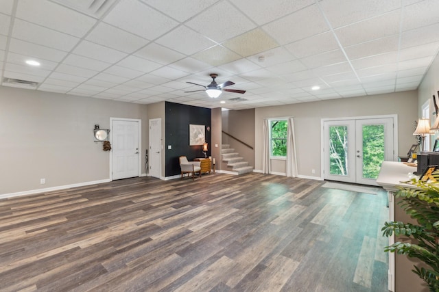 unfurnished living room featuring wood finished floors, stairway, baseboards, a ceiling fan, and a paneled ceiling