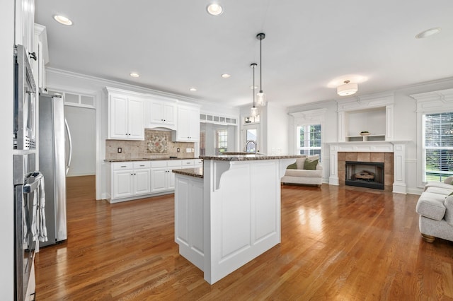 5417 Cavendish Dr, Murfreesboro, TN 37128 - kitchen with open floor plan, a breakfast bar area, light wood-style floors, ornamental molding, and white cabinetry